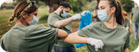 Volunteers cleaning up a park with masks on