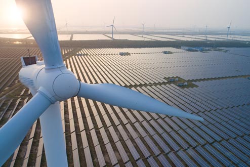 Aerial view of windmill over a solar panel field