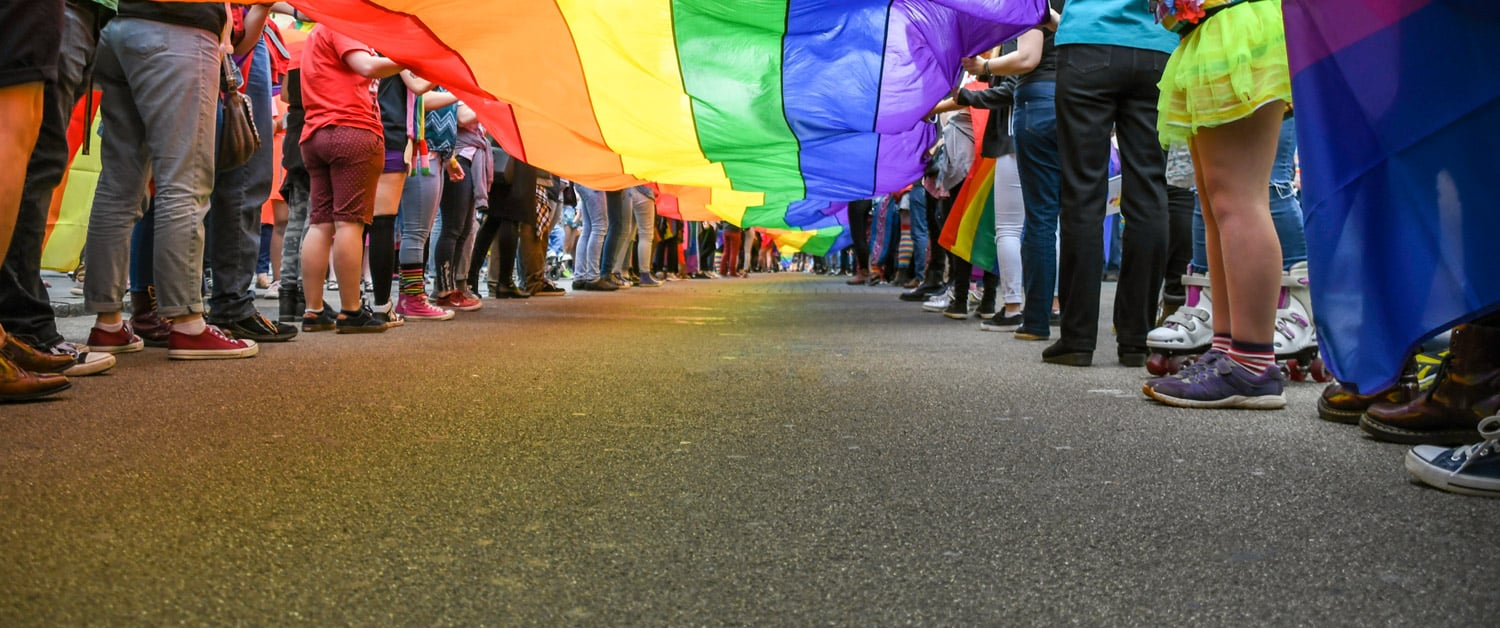 a group of people standing next to a woman holding a colorful umbrella