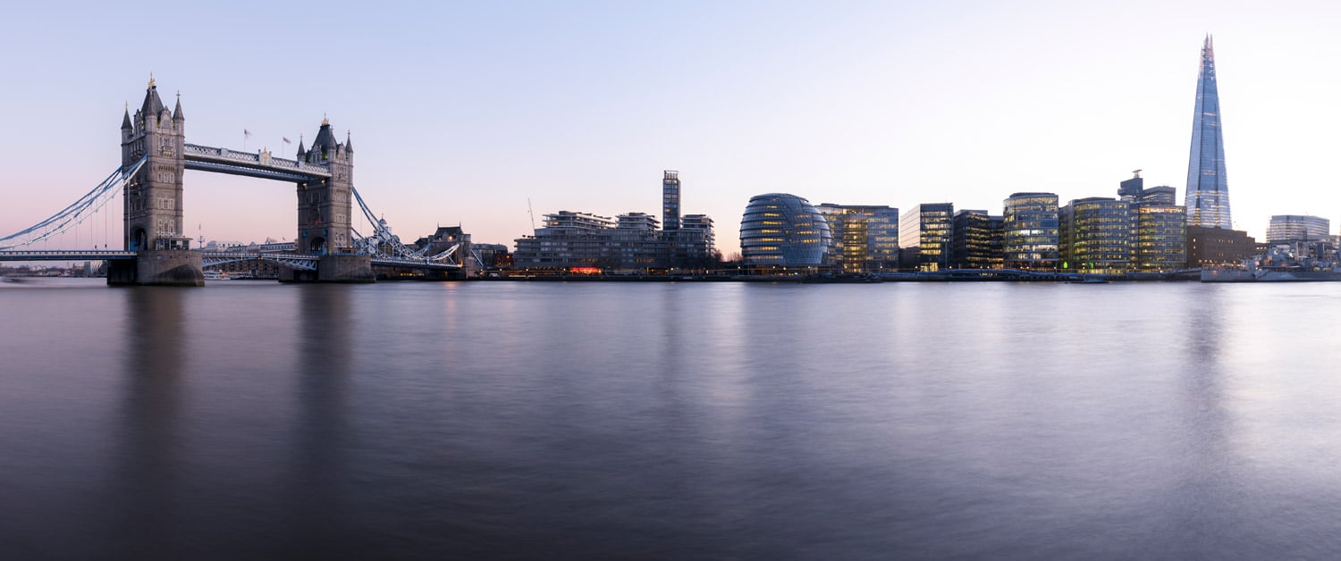 a bridge over a body of water with a city in the background