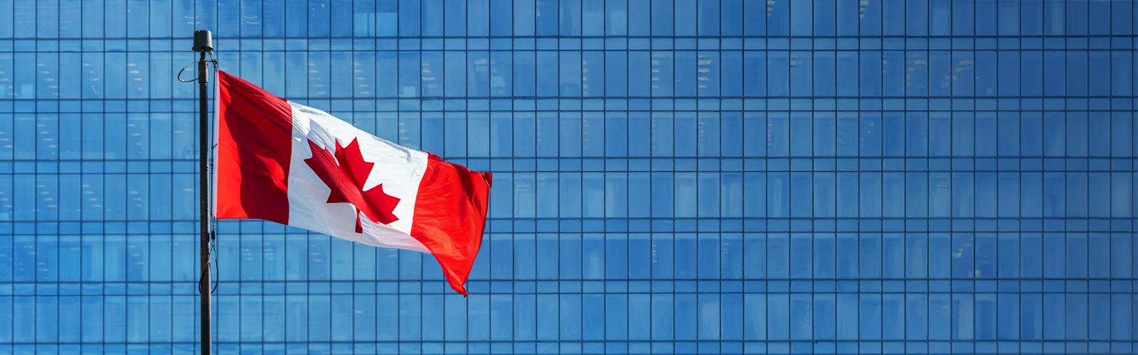 Canadian flag with a blue skyscraper in behind 