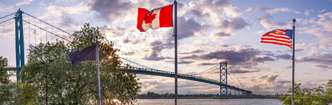 Canadian and America flags against a dramatic sky | Drapeaux du Canada et de l'Amérique contre un ciel dramatique