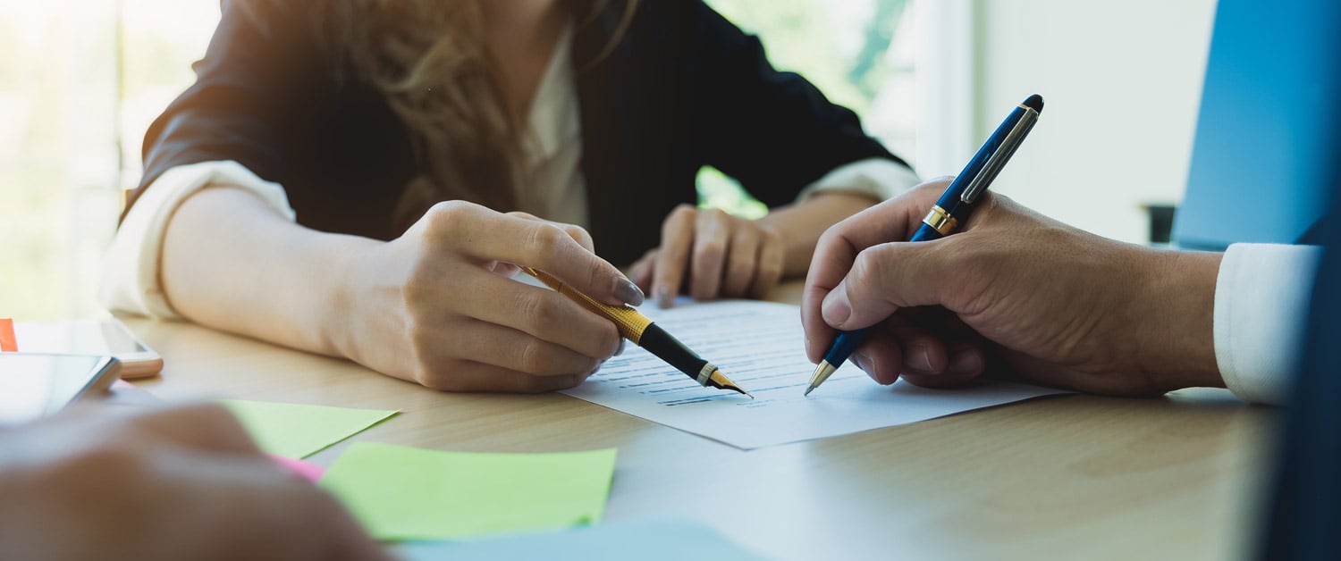 deux personnes  qui pointent des mots sur une feuille avec des stylos